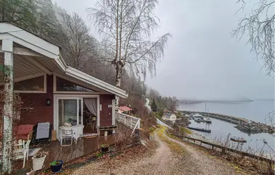 a house on a road next to a lake at Nice Home In Vallavik With Wifi in Kaland