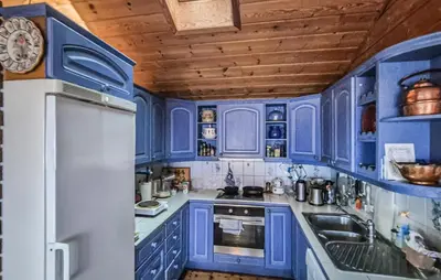 a blue kitchen with blue cabinets and a refrigerator at Nice Home In Vallavik With Wifi in Kaland