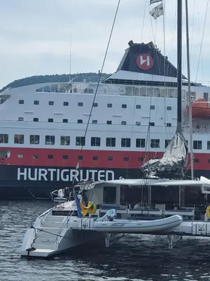 a boat in the water next to a large ship at Sentralt,unikt lite bergenshus med sjel på fine Nøstet! in Bergen