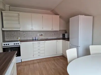 a kitchen with white cabinets and a white refrigerator at Your home in Kristiansund in Kristiansund