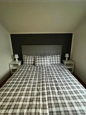a bed with a plaid bedspread and two night stands at Your home in Kristiansund in Kristiansund