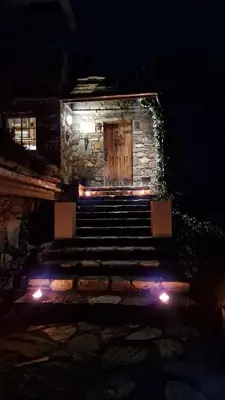 a stone building with a wooden door and stairs at night at Haven Fortress