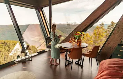 a woman standing in a room with a table in front of windows at Eagle Nest Eco Lodge in Sel