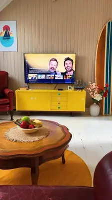 a living room with a television on a yellow dresser at Authentic top floor pearl in the city Center in Ålesund