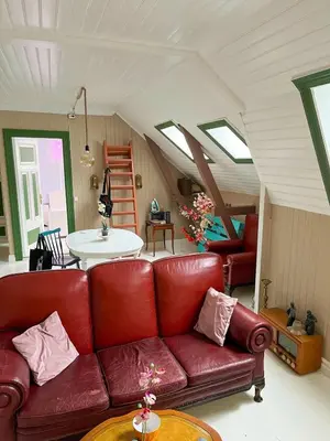 a living room with a red couch and a table at Authentic top floor pearl in the city Center in Ålesund