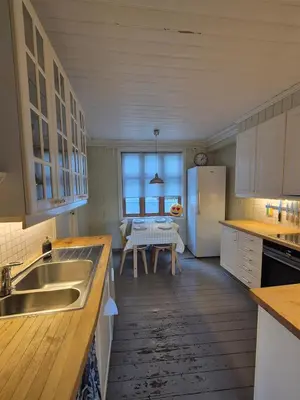 a kitchen with a sink and a refrigerator and a table at Penthouse apartment with garden and amazing view, in Bergen