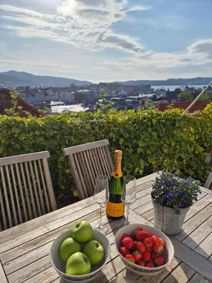 a table with a bottle of wine and bowls of fruit at Penthouse apartment with garden and amazing view, in Bergen