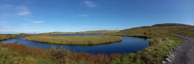 a river in the middle of a field with hills at Unik og moderne microhytte med utsikt mot havet 40 A in Longva