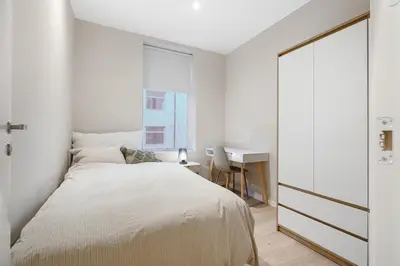 a white bedroom with a bed and a desk at Large apartment, central and quiet in Ålesund in Ålesund