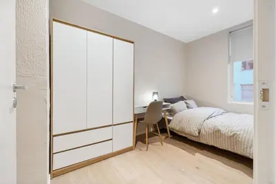 a bedroom with a bed and a desk with a chair at Large apartment, central and quiet in Ålesund in Ålesund
