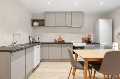 a kitchen with white cabinets and a wooden table at Large apartment, central and quiet in Ålesund in Ålesund