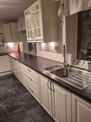 a kitchen with white cabinets and a stainless steel sink at Holiday home Hemnskjel in Hitra