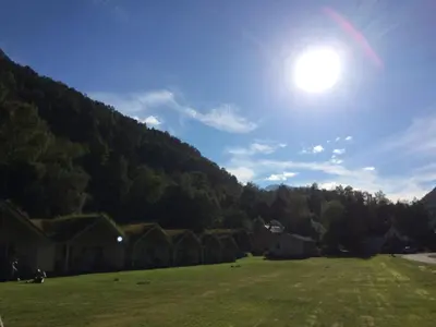 a field with houses and the sun in the sky at Hjelledalen Hyttesenter in Hjelle