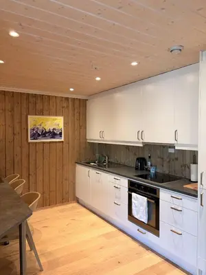 a kitchen with white cabinets and a wooden ceiling at Apartment in the Center of Geilo in Geilo