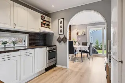 a kitchen with white cabinets and a dining room with a table at Enebolig med 5 soverom in Lii