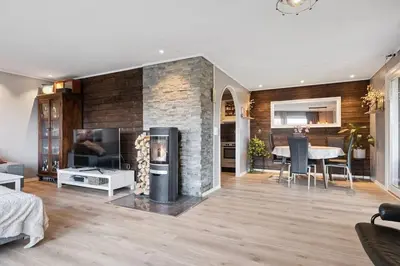 a living room with a fireplace and a dining room at Enebolig med 5 soverom in Lii
