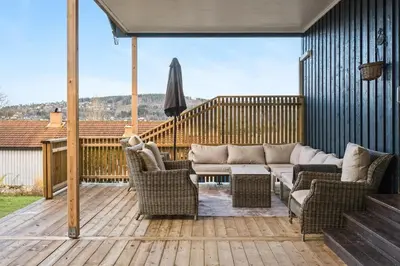 a patio with a couch and chairs on a deck at Enebolig med 5 soverom in Lii