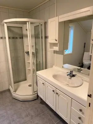 a white bathroom with a shower and a sink at Charming sea view in Bergen