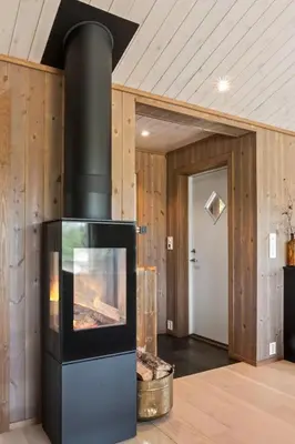 a fireplace in a living room with wooden walls at Solglimt, mountain cabin in Golsfjellet with jacuzzi in Gol