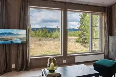 a living room with large windows with a view at Solglimt, mountain cabin in Golsfjellet with jacuzzi in Gol