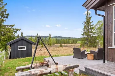 a patio with a swing and chairs on a house at Solglimt, mountain cabin in Golsfjellet with jacuzzi in Gol