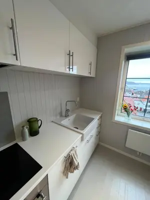 a white kitchen with a sink and a window at Nice and central apartment in Sandviken with sea view in Bergen