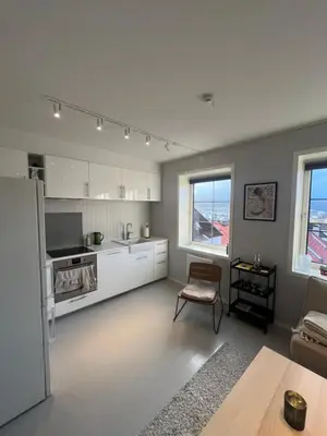 a kitchen with white cabinets and a table and a chair at Nice and central apartment in Sandviken with sea view in Bergen