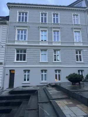 a large gray building with white windows on a street at Apartment in the heart of Bergen in Bergen