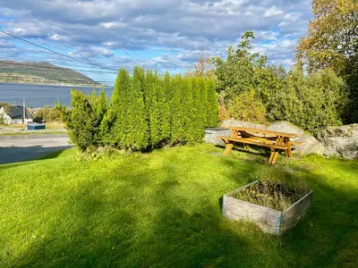 a picnic table in the grass next to the water at 5 Bedroom House at Hakallestranda in Sandvik