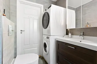 a bathroom with a washer and dryer next to a sink at Centrum apartment 1 in Ålesund