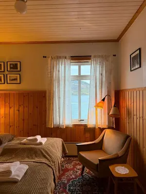 a bedroom with a bed and a chair and a window at Davik Fjordparadis