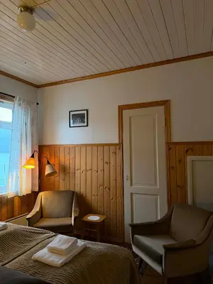 a bedroom with a bed and a chair and a window at Davik Fjordparadis