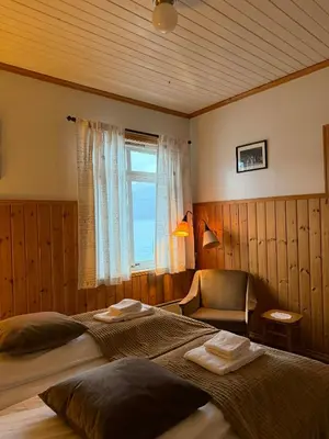 a bedroom with a bed and a chair and a window at Davik Fjordparadis