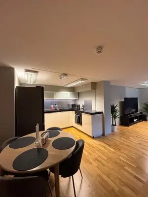 a living room with a table and a kitchen at Modern apartment in central Trondheim in Trondheim