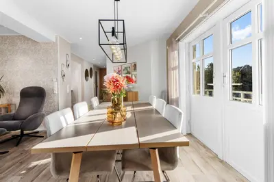 a dining room table with a vase of flowers on it at Konsul Moes Gate 4 in Verdal
