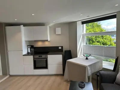 a kitchen with white cabinets and a table and a window at Apartment centrally with garage and terrace in Ålesund