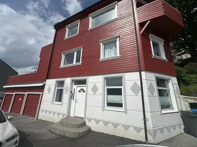 a red and white house with a white door at Apartment centrally with garage and terrace in Ålesund