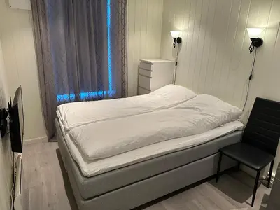 a small bedroom with a bed and a chair at Apartment centrally with garage and terrace in Ålesund