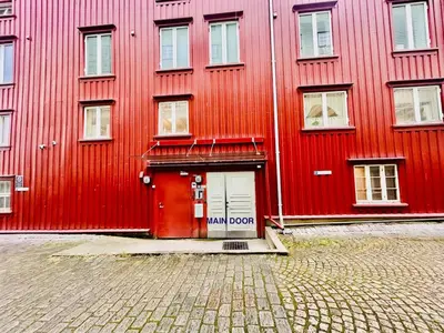 a red building with a red door next to a street at Riverside studioapartment 100m from trainstation! in Trondheim