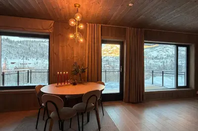 a dining room with a table and chairs and windows at Modern ski-in-ski-out apartment in Hemsedal in Hemsedal