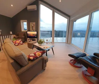 a living room with a couch and a tv at Flott leilighet med nydelig utsikt i et stille og rolig boligområde in Bergen