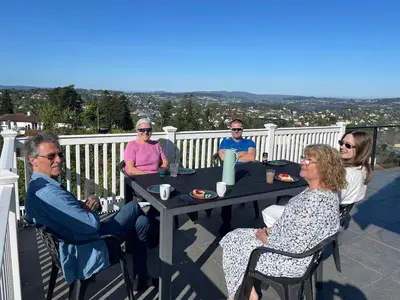 a group of people sitting at a table on a balcony at Flott leilighet med nydelig utsikt i et stille og rolig boligområde in Bergen