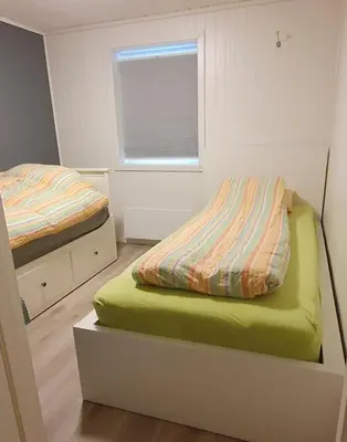 a small bedroom with two beds and a window at Flott leilighet med nydelig utsikt i et stille og rolig boligområde in Bergen