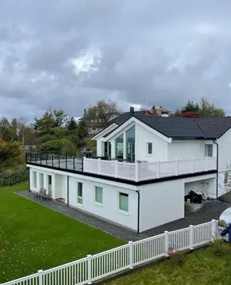 a white house with a black roof at Flott leilighet med nydelig utsikt i et stille og rolig boligområde in Bergen