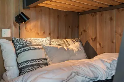 a bed with pillows in a room with wooden walls at Trysiltunet 28A by Vacation Trysil in Trysil
