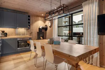 a kitchen with a wooden table and white chairs at Trysiltunet 28A by Vacation Trysil in Trysil