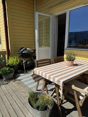 a wooden table and chairs on a porch with a grill at Charming apartment with balcony and view! in Ålesund