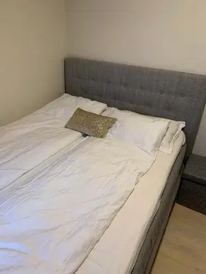 a large white bed with a gray headboard at Cozy apartment in the middle of Bergen city center in Bergen