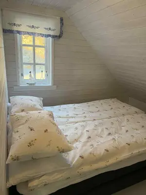 an unmade bed in a room with a window at Cabin by the lake in Sveio