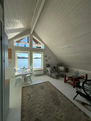 a living room with a large window and a table at Cabin by the lake in Sveio
